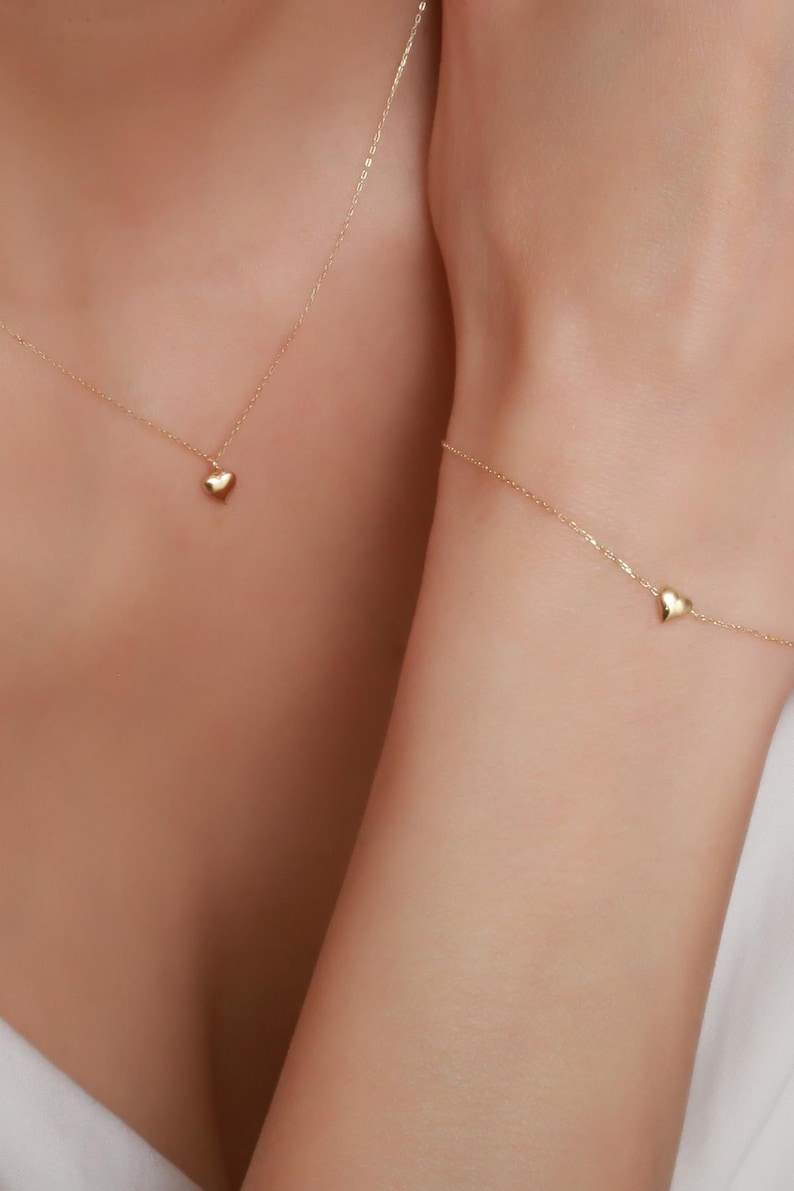 May include: A gold necklace and bracelet with small heart charms.