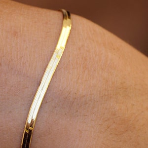 May include: A gold chain bracelet with a snake chain design.