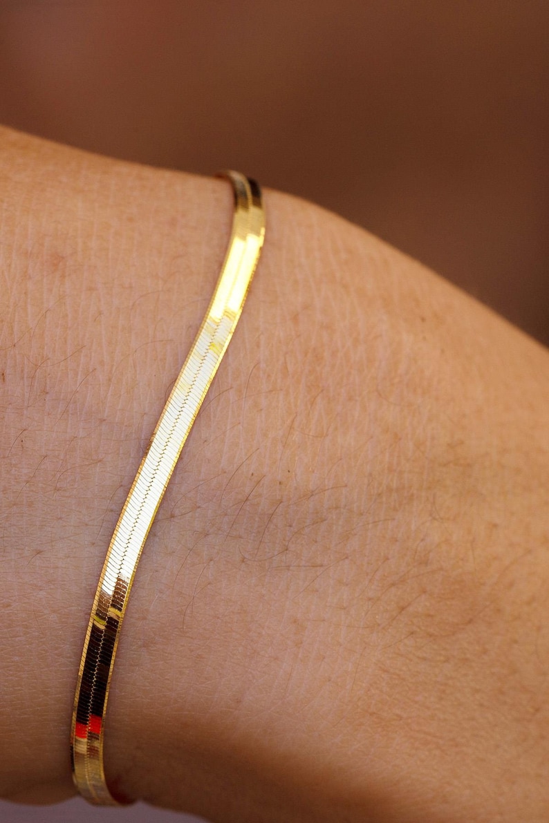 May include: A gold chain bracelet with a snake chain design.
