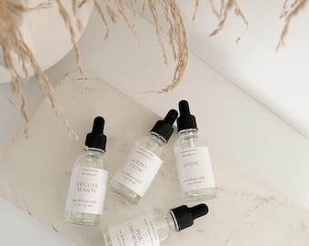 May include: Four small glass bottles with black dropper tops and white labels. The labels have the text "A Mood Series" and different scents: "Golden Glow", "Sweater Season", "Serene", and "Pinky Champagne". Each bottle contains 1 oz (30 ml) of car diffuser refill.