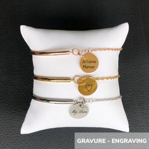 Puede incluir: Tres pulseras de brazalete doradas con dijes grabados. El dije superior dice "Je t'aime Maman", el dije del medio tiene un corazón y el dije inferior dice "My Love".