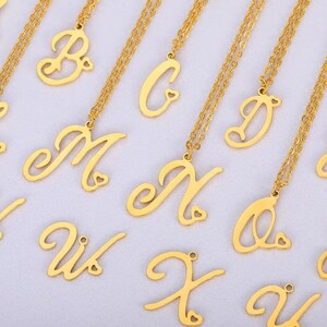 May include: A set of gold-toned necklaces with cursive letter charms. Each charm has a small heart cutout. The letters include B, C, D, M, N, O, U, X, and Y.
