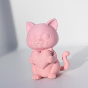 Pode incluir: Uma figura de gato rosa segurando um coração rosa. O gato tem uma expressão doce e uma cauda pequena.