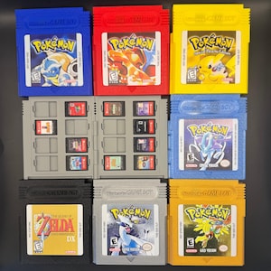 May include: A collection of Nintendo Game Boy cartridges including blue, red, yellow, light blue, black, silver, and gold versions of Pokémon and Zelda games, alongside a gray plastic storage case holding eight smaller Nintendo Switch game cards.