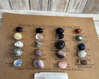 May include: A set of 12 tumbled crystals with their corresponding names and properties listed on a brown card. The crystals include amethyst, howlite, clear quartz, jasper, lepidolite, green aventurine, lapis lazuli, moonstone, opalescent, pink tourmaline, rose quartz, and smoky quartz. The set also includes a selenite stick.