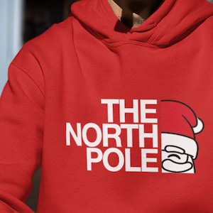 May include: Red hooded sweatshirt with white text that reads "THE NORTH POLE" and a cartoon Santa Claus face.