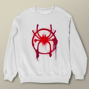 Puede incluir: Sudadera blanca con un dise&ntilde;o de pintura en aerosol roja y morada de una ara&ntilde;a en un c&iacute;rculo.