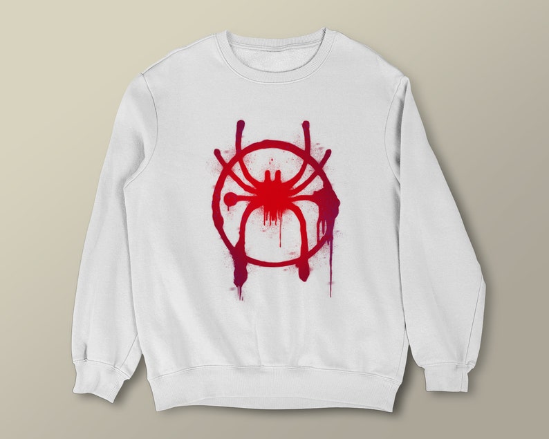 Puede incluir: Sudadera blanca con un dise&ntilde;o de pintura en aerosol roja y morada de una ara&ntilde;a en un c&iacute;rculo.