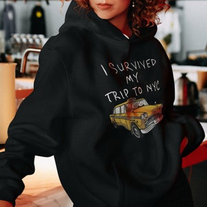May include: Black hoodie with a white graphic of a yellow taxi cab and the text "I survived my trip to NYC".