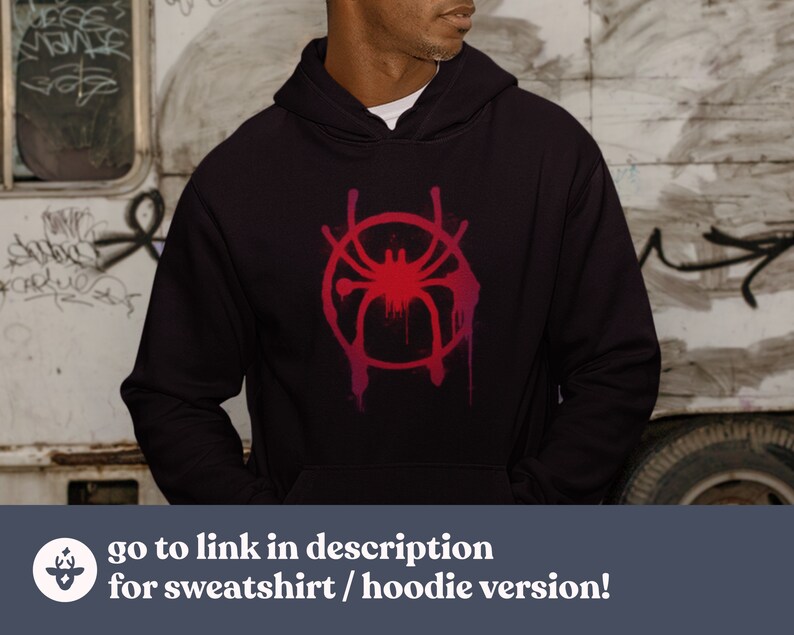 May include: A black hoodie with a red and pink stylized spider graphic. The graphic is in the shape of a circle with a spider in the center. The spider has eight legs and a red body. The hoodie has a drawstring hood and a kangaroo pocket.