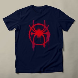 May include: A navy blue t-shirt with a red and pink spray paint design of a spider in a circle. The design is reminiscent of the Spider-Man: Into the Spider-Verse movie.