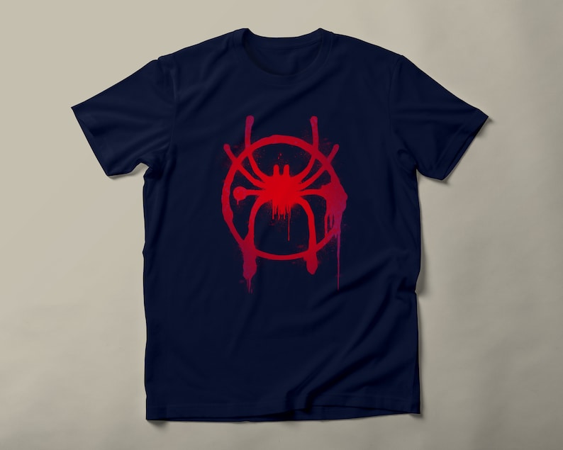 May include: A navy blue t-shirt with a red and pink spray paint design of a spider in a circle. The design is reminiscent of the Spider-Man: Into the Spider-Verse movie.