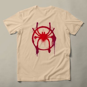 May include: A beige t-shirt with a red and purple spray paint design of a spider in a circle.