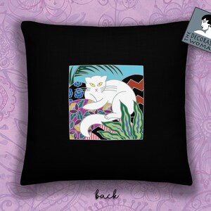 May include: Black throw pillow with a white cat illustration in a colorful, geometric design. The cat is lying down with its tail curled around its body. The design includes green, blue, pink, and yellow colors. The pillow has the text "The Decorated Woman" on the back.