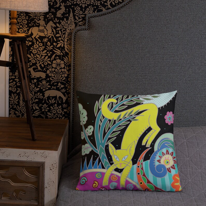 Peut inclure: Un chat jaune avec des motifs floraux verts, bleus et roses sur un fond noir. Le chat est assis sur un cercle &agrave; motifs roses et bleus.