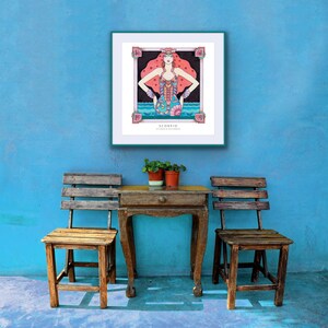 May include: A framed illustration of the astrological sign Scorpio, featuring a woman with red hair and a blue and green scorpion tail. The frame is teal and the background is a light blue wall. Two wooden chairs and a small wooden table with a drawer are in the foreground.