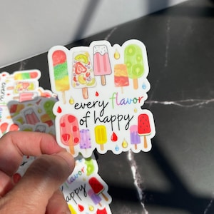 May include: A white sticker with a colorful illustration of popsicles and the text "every flavor of happy".