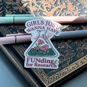 May include: A die-cut sticker featuring a laboratory flask containing pink flowers and green liquid. A DNA strand wraps around the neck of the flask. The text reads GIRLS JUST WANNA HAVE FUNDING for Research in maroon and green lettering.