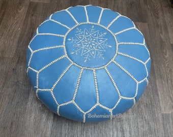May include: A blue leather pouf with white stitching and a white embroidered snowflake design.
