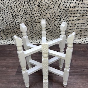 以下が含まれることがあります： 装飾的な彫刻デザインが施された白い木製の折りたたみテーブル。テーブルは4本の脚と円形の天板を持っています。