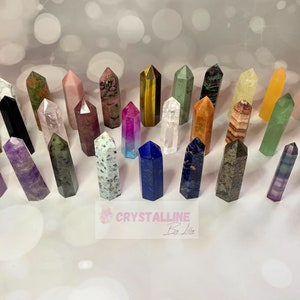 May include: A collection of 25 colourful crystal points, including amethyst, rose quartz, tiger's eye, and clear quartz. The points are arranged in a semi-circle on a white surface.  Crystalline By Lily.
