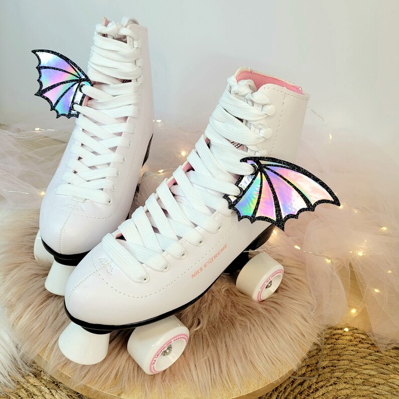 May include: White roller skates with pink accents and iridescent wings attached to the laces. The skates have the text "Miss Extreme" on the side.