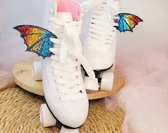 May include: White roller skates with rainbow glitter wings attached to the laces. The skates have pink lining and black wheels.