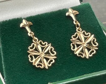 May include: A pair of gold earrings with a delicate floral design. The earrings are in a green velvet box.