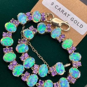 May include: A 9 carat gold bracelet with oval-shaped opals and smaller purple gemstones. The bracelet has a clasp closure.