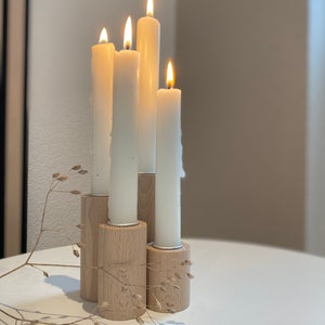 May include: A set of four white candles in wooden candle holders. The candles are lit and the holders are arranged in a staggered pattern.
