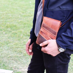 May include: A brown leather crossbody bag with a strap. The bag has a flap closure and a stitched design.