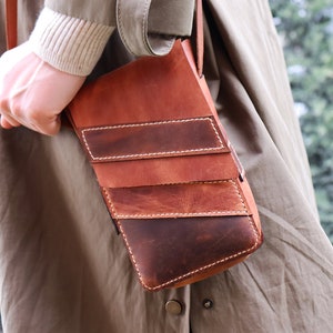 May include: A brown leather crossbody bag with multiple stitched panels and a flap closure.