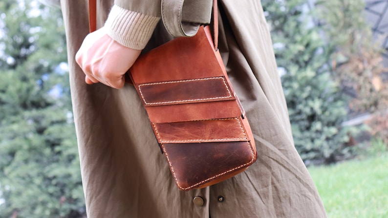 May include: A brown leather crossbody bag with multiple stitched panels and a flap closure.