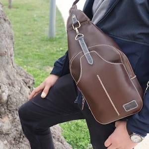 Puede incluir: Un bolso bandolera de cuero marr&oacute;n con cierre de solapa y un bolsillo con cremallera. El bolso tiene una correa ajustable para un ajuste c&oacute;modo en el cuerpo.