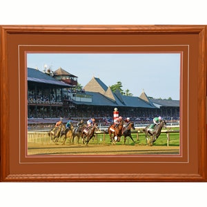 May include: A photograph of a horse race at a racetrack. The horses are running towards the finish line, with jockeys in colorful silks. The grandstand is in the background, with spectators watching the race.