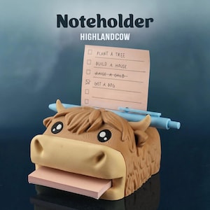 May include: A Highland cow-shaped notepaper holder in brown and tan, with a stack of pink sticky notes. It features a pen and a list with the text "Plant a tree", "Build a house", "Raise a child", and "Get a dog". The text "Noteholder HIGHLANDCOW" is above the cow.