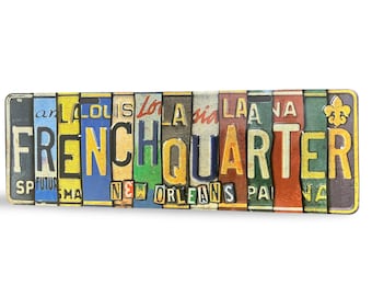 Puede incluir: Un letrero rectangular con las palabras "FRENCH QUARTER" escritas con placas de matrícula coloridas. El letrero tiene un aspecto envejecido y vintage, con "NEW ORLEANS" en la parte inferior.