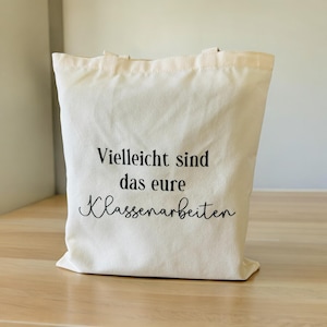 Könnte beinhalten: Eine weiße Stofftasche mit schwarzem Text, der "Vielleicht sind das eure Klassenarbeiten" lautet.