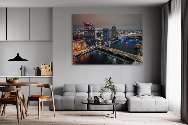 May include: An aerial view of a city skyline at night. The city is lit up with lights, and there is a river running through the middle of the city. There are several bridges crossing the river.