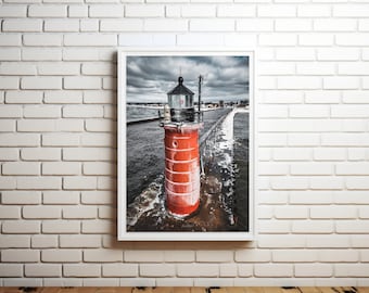 May include: A red and white lighthouse stands tall on a pier extending into a choppy, icy blue lake. The lighthouse has a black roof and a black lantern on top. The sky is overcast with dark clouds.