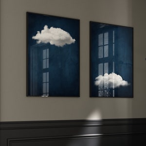 Op de afbeelding: Twee ingelijste prints met een donkerblauwe achtergrond en witte wolken. De wolken bevinden zich op verschillende posities op elke print.