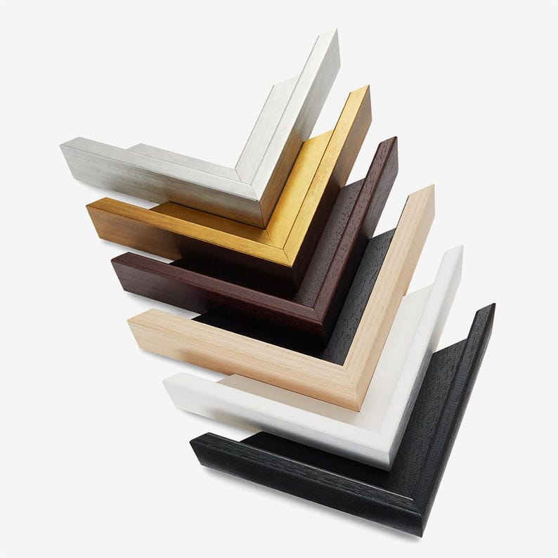 May include: A collection of wooden picture frame corners in various colors, including silver, gold, brown, black, and white. The frames are arranged in a layered, angled composition, showcasing the different finishes and styles.