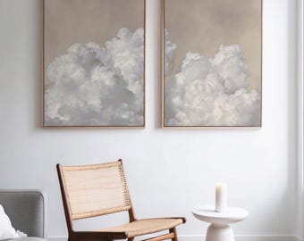 May include: Two framed paintings of a cloudy sky in shades of gray and white. The paintings are hung on a white wall above a wooden chair and a white side table.