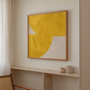 May include: A framed abstract painting with a yellow and white geometric design. The painting is hanging on a white wall above a shelf with two small ceramic pots.