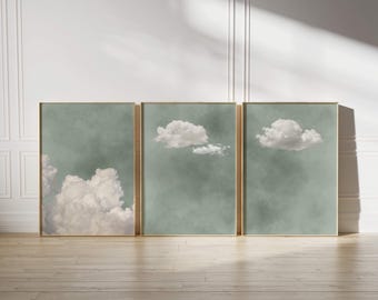 May include: Three framed prints of clouds against a light green background. The clouds are white and fluffy, and the frames are a light wood color.