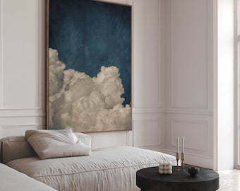 May include: A large abstract painting of white clouds against a dark blue sky. The painting is hanging on a white wall in a modern living room with a white couch and a black coffee table.