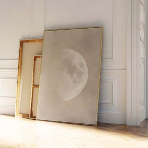May include: A framed print of a close-up of the moon in shades of grey and white against a light beige background.