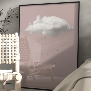 May include: An abstract art print in pink and white featuring a white cloud and gold glitter rain. The print is framed in a black frame and is hanging on a wall.