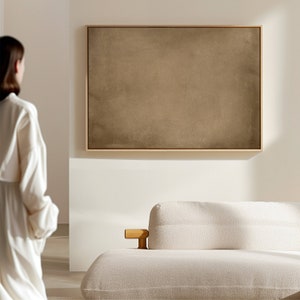 May include: A white couch with a wooden armrest in a modern living room with a framed abstract painting on the wall.