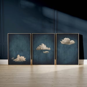 May include: Three framed prints with a dark blue background and white clouds. The clouds are different shapes and sizes.